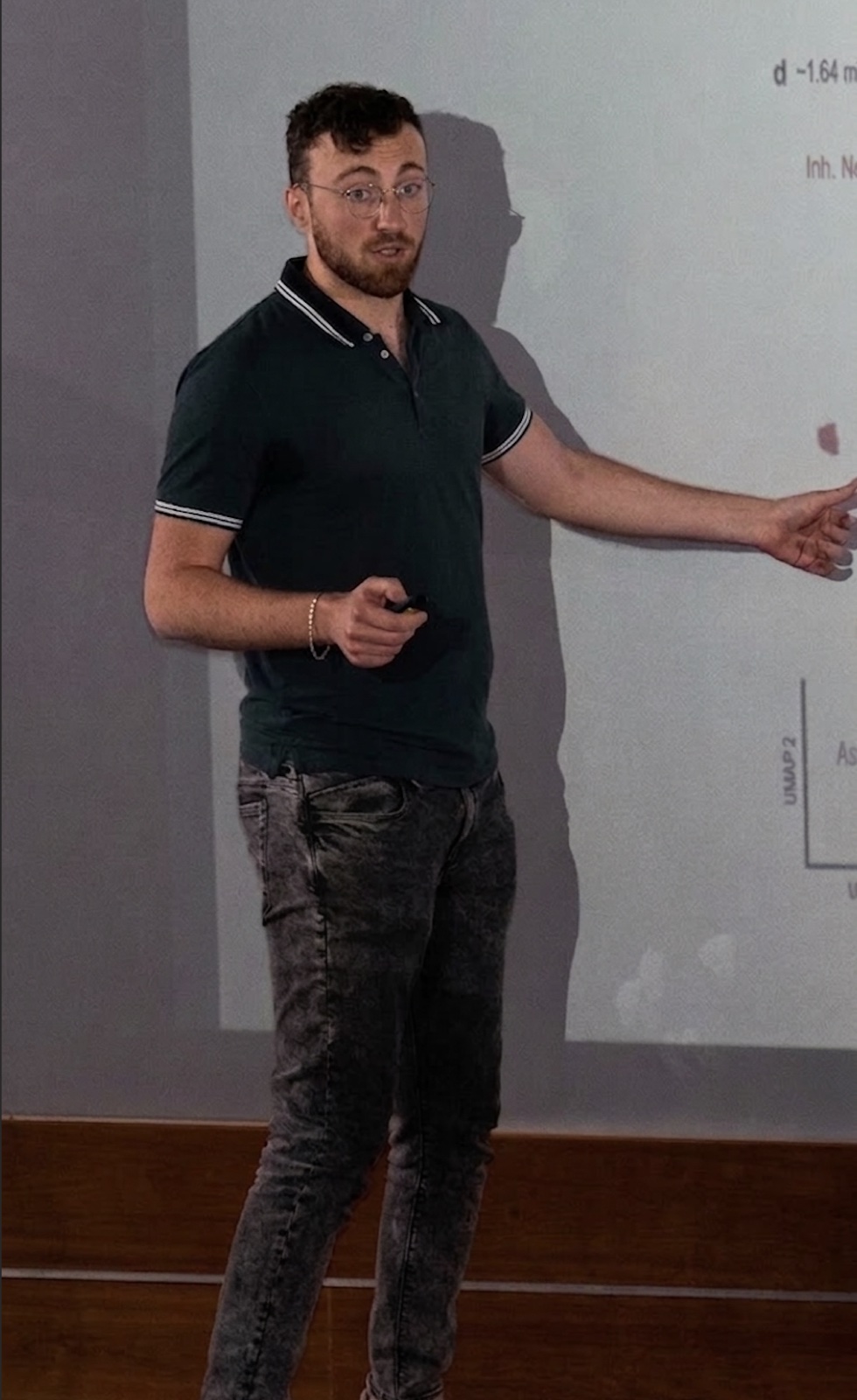 Mid-talk, turning to gesture at a projected slide of a UMAP scatter plot.